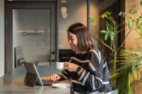 a woman sitting at a table with a laptop computer at The Millennials Kyoto in Kyoto