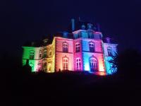 a house lit up in purple and green at château de Locquéran Pierres et filets bleus in Plouhinec