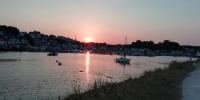 a sunset over a harbor with boats in the water at château de Locquéran Pierres et filets bleus in Plouhinec