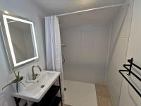 Baño blanco con lavabo y espejo en La Maison Manole, en Jard-sur-Mer