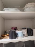 a shelf with plates and cups and utensils at L&#39;appartement Idéal 4 voyageurs in Boulogne-Billancourt