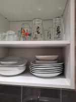 a white cabinet filled with plates and glasses at L&#39;appartement Idéal 4 voyageurs in Boulogne-Billancourt