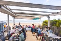 a group of people sitting at tables at a beach restaurant at Hôtel Les Charmettes - Saint Malo in Saint Malo