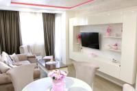 Una sala de estar con una mesa y sillas y un televisor. en Apartman Bajka, en Zlatibor