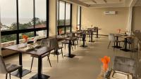 a restaurant with tables and chairs and large windows at SKY KENAKO HOTEL in Kribi