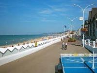 a beach with people walking on the sand and the ocean at Appartement Villers-sur-Mer, 2 pièces, 4 personnes - FR-1-712-24 in Villers-sur-Mer