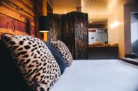 a bedroom with a bed with leopard pillows and a bathroom at Pousada Aberdeen in Campos do Jordão