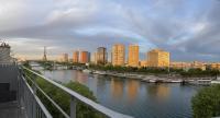 a river with boats in a city with tall buildings at Appartement vue Tour Eiffel paris 16 Eme in Paris