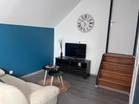 a living room with a couch and a clock on the wall at Appartement Amiens-Camon in Camon