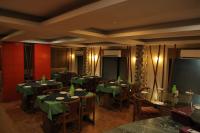 a restaurant with tables and chairs with green table cloth at Hotel Gokul in Gandhidham