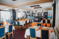 un restaurante con mesas blancas y sillas azules en MOTEL POPAS TALMACIU, en Tălmaciu