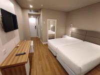 Una habitación de hotel con dos camas y un televisor. en Hotel Cristal Caldas, en Caldas da Rainha