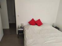 a white bed with two red pillows on it at Appartement de 2 chambres avec vue sur la ville terrasse amenagee et wifi a Saint Ouen in Saint-Ouen