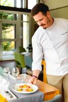 a man is preparing a plate of food on a table at Logis Hotel Le Relais De La Poste Restaurant Le Fil du Temps in Thury-Harcourt