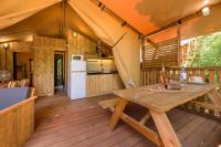 a kitchen and dining area of a tent with a wooden table at Camping U Pirellu in Porto-Vecchio