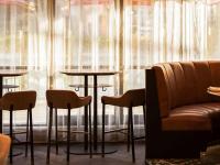 a bar with two tables and a couch in front of a window at The Playford Adelaide - MGallery in Adelaide