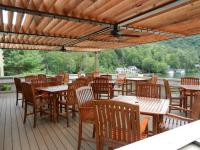 een terras met houten tafels en stoelen met uitzicht op het water bij Brewer Hollow in Lake Lure
