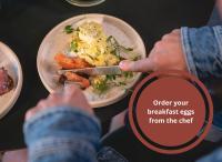 オーフスにあるHotel GUESTapartのナイフを使って皿の上の食べ物を食べる人