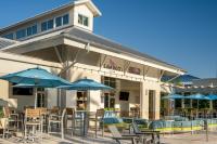 Un restaurante con mesas, sillas y sombrillas. en SpringHill Suites by Marriott Orlando at FLAMINGO CROSSINGS Town Center-Western Entrance, en Orlando