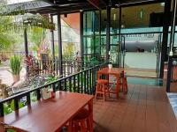 un patio con mesas y sillas de madera en un edificio en บีฮายฮิลล์ รีสอร์ต, en Ban Khlong Kua