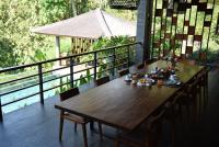 Una mesa y sillas de madera en un balcón. en Bali River Retreat, en Perean