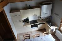 a small kitchen with white cabinets and a table and chairs at Chalet Beaujon Chapelle-des-Bois in Chapelle-des-Bois