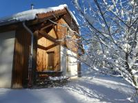 a log cabin in the snow with a snow covered tree at Chalet Beaujon Chapelle-des-Bois in Chapelle-des-Bois
