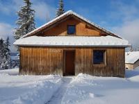 a wooden cabin in the snow with a door at Chalet Beaujon Chapelle-des-Bois in Chapelle-des-Bois