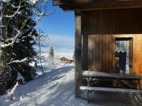 a wooden cabin with a bench in the snow at Chalet Beaujon Chapelle-des-Bois in Chapelle-des-Bois