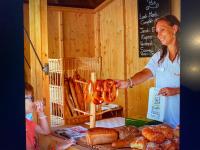 a woman standing in front of a table with bread at MOBIL HOME Clim BOOFZHEIM 6 PERSONNES 3 CHAMBRES LE RIED 3 ETOILES PROCHE EUROPA PARK in Boofzheim