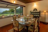 ein Esszimmer mit Tisch und Stühlen und einem Fenster in der Unterkunft Emerald by Nature Resorts and Stays in Udagamandalam