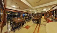 Un restaurante con mesas y sillas en una sala. en Hotel Mahabs, en Mahabalipuram