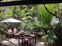 two tables and chairs in a garden with palm trees at Mangueira Boutique Hotel Moreré in Moreré