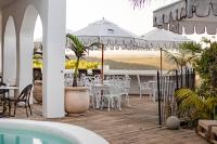 um pátio com mesas e cadeiras e uma piscina em The Ivory Haus em Plettenberg Bay