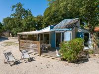 une petite maison avec deux chaises et une terrasse dans l&#39;établissement Camping Le Bois Fleuri, à Argelès-sur-Mer