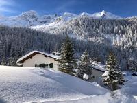a house in the snow with mountains in the background at Apartment Paletti 23 in Enzingerboden