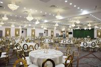 Un salón de banquetes con mesas y sillas blancas y candelabros. en Ramada by Wyndham DFW Airport, en Irving