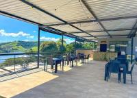een terras met tafels en stoelen en uitzicht op het water bij Pousada Villa Shalom in Igaratá