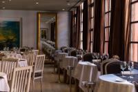 Un comedor con mesas y sillas blancas y ventanas. en Hotel Blancafort Spa Termal, en La Garriga
