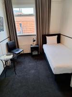 a hotel room with a bed and a chair and a window at Stad &amp; Strandhotel Elisabeth in Vlissingen
