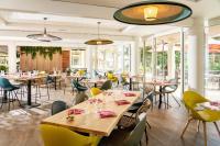 un restaurant avec des tables, des chaises et des fenêtres dans l'établissement Hôtel Valdys Thalasso & Spa - les Pins, à Saint-Jean-de-Monts