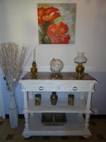 a white console table with a vase and a painting at Le Clos Fleuri in Caumont