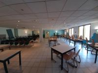 Un comedor con mesas y sillas y ventanas. en Centre de Vacances Le Hameau Rollot, en Barèges