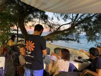 Testa di Monaco - Basic Beach Accommodations في كابو دورلاندو: مجموعة من الناس يجلسون على طاولة بجوار الماء