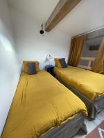two beds in a room with yellow sheets at Le Taurillou 
