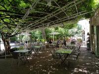 an outdoor patio with tables and chairs and people at Logis Hotel Restaurant la Ferme in Avignon