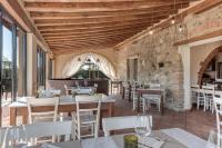 a restaurant with white tables and chairs and a stone wall at Locanda dell'Aioncino in Bibbona