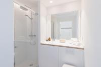 a white bathroom with a shower and a sink at Les Appartements de Grenoble in Grenoble