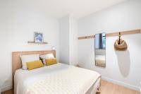 a white bedroom with a bed with yellow pillows at Les Appartements de Grenoble in Grenoble