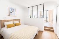 a white bedroom with a large bed with yellow pillows at Les Appartements de Grenoble in Grenoble